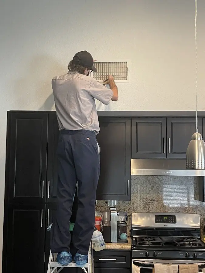 Technician inspecting an air vent during HVAC service in Edgewater